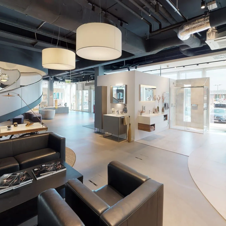 Moderner, offener Empfangsbereich mit schwarzer Ledercouch, weißen Wänden und großen Fenstern in einem Bürogebäude