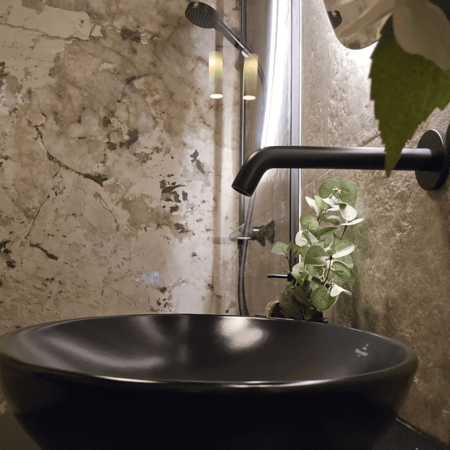 Modernes Badezimmer mit begehbarer Dusche, schwarzem Waschbecken auf schwarzer Ablage und rundem beleuchtetem Spiegel