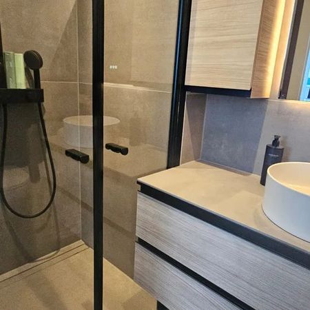 Modernes Badezimmer mit hängendem Waschbecken, beleuchtetem Spiegel und Holzschränken unter einer Dachschräge