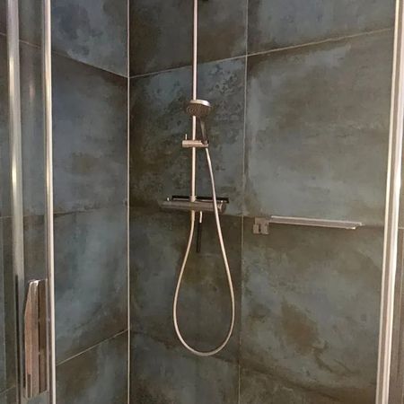 Dusche mit Glasabtrennung in einem Badezimmer mit grauen Fliesen