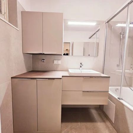 Modernes Badezimmer mit rechteckiger Badewanne, Glas-Duschabtrennung, Waschbecken mit Armatur und großem Spiegel