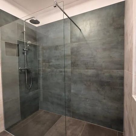 Moderne begehbare Dusche mit Glasabtrennung, Regendusche und dunkelgrauen Wandfliesen