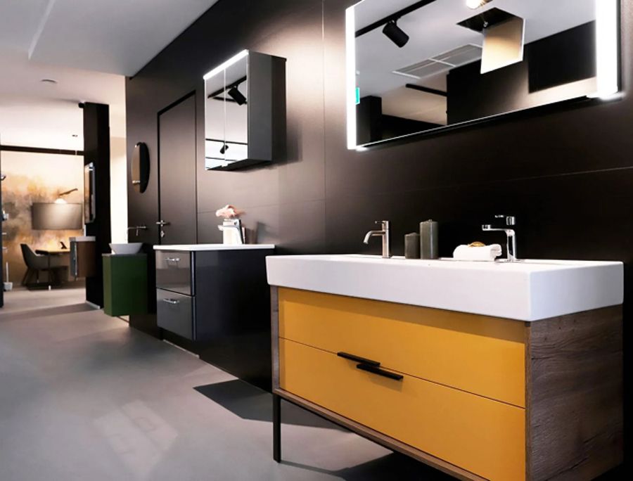 Moderne Badezimmer mit mehreren Waschbecken und Spiegeln, darunter ein Waschbecken mit gelber Front und schwarzem Griff